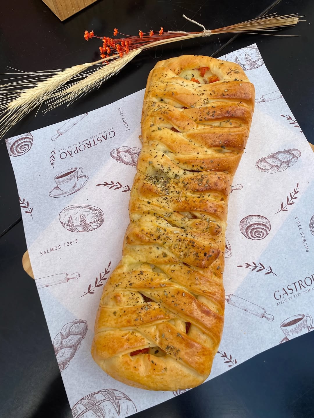 Trança recheada do Gastropão sobre papel de embrulho com logo e decoração de trigo